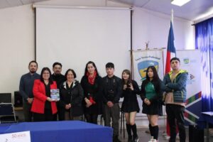 Grupo de personas posando frente a un lienzo de "Liceo Técnico Profesional", con una bandera chilena a la derecha.