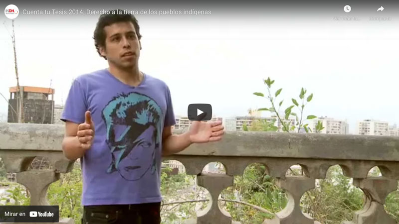 Hombre con camiseta de David Bowie hablando frente a una barandilla con vista a la ciudad.