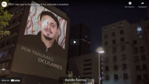 Edificio con proyección nocturna de un hombre con un parche ocular, acompañado del texto "Por traumas oculares".