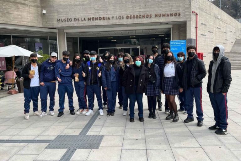 Grupo de personas con mascarillas posando frente al Museo de la Memoria y los Derechos Humanos.