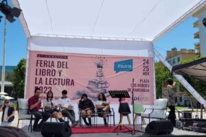 Personas en un escenario al aire libre en la "Feria del Libro y la Lectura", con un cartel al fondo anunciando el evento en Rancagua, noviembre 2023.
