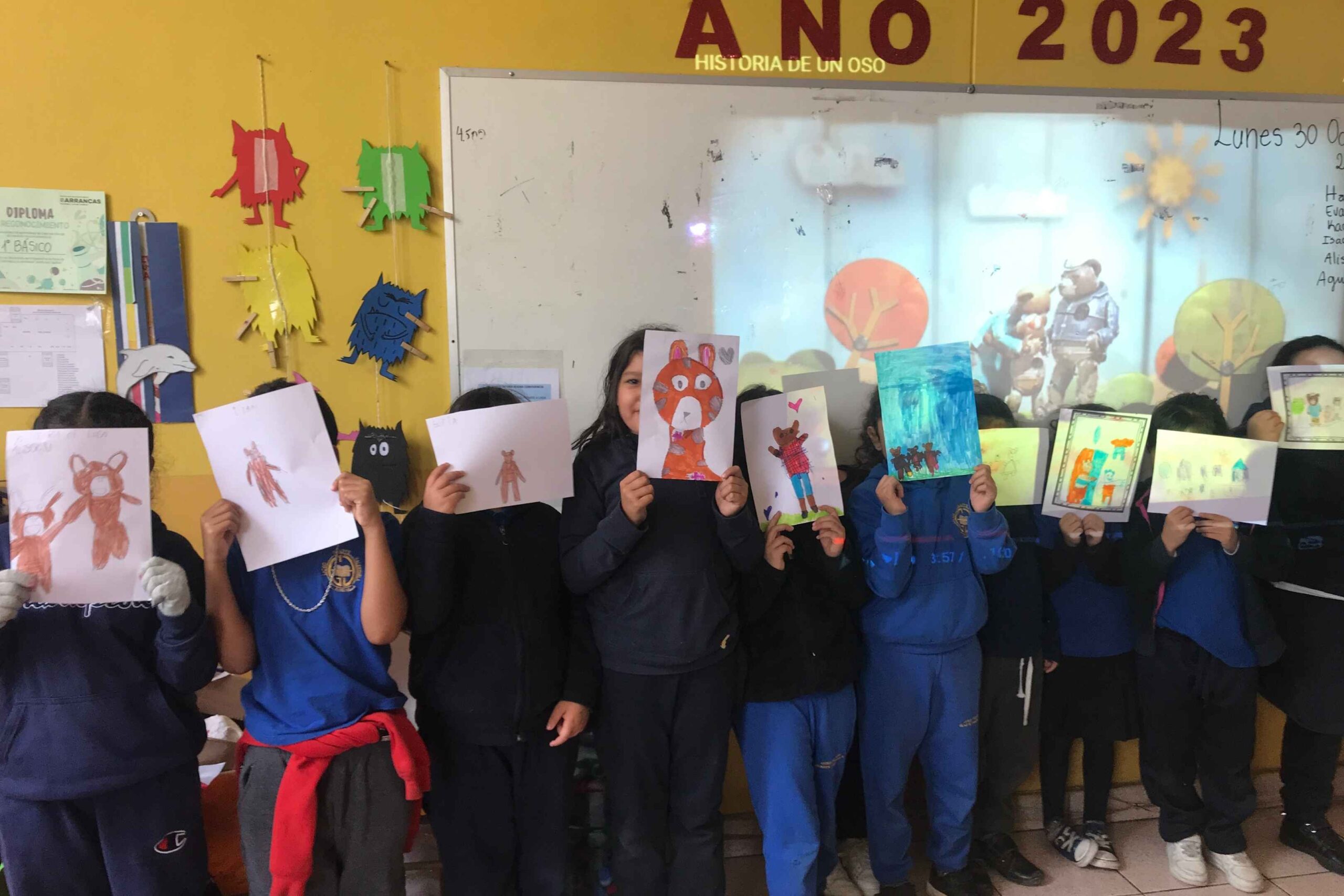 Niños en un aula mostrando dibujos de osos.