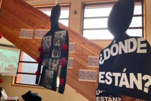 Siluetas negras colgantes con la pregunta "¿Dónde están?" en letras blancas; fondo de carteles con imágenes y texto.