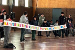 Grupo de personas sosteniendo una pancarta colorida que dice: "Una papeleta de votos es más fuerte que una bala de fusil".