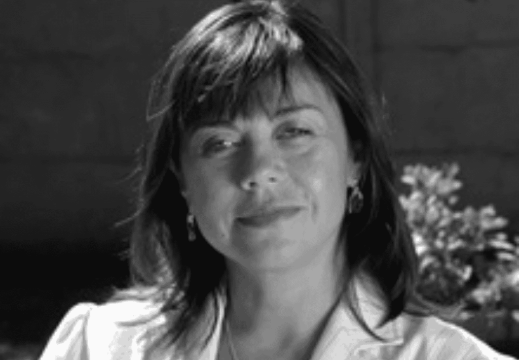 Mujer de cabello oscuro sonr&iacute;e ligeramente, retrato en blanco y negro.