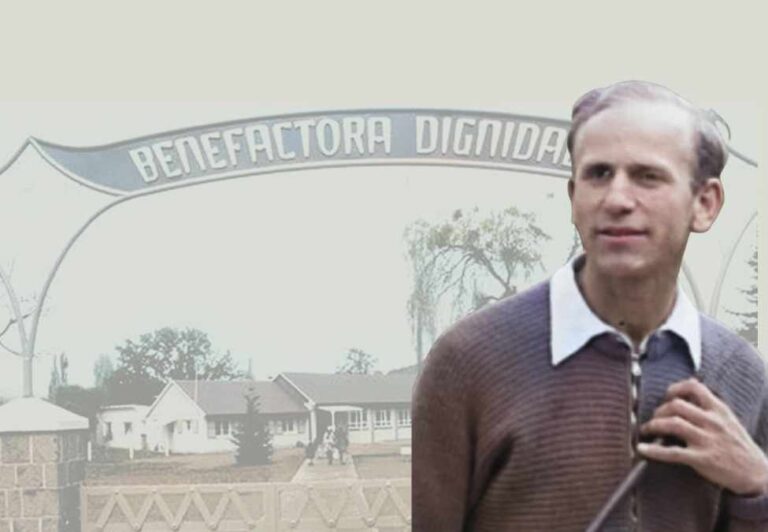 Persona de pie frente a una entrada con un letrero que dice "Benefactora Dignidad" y un edificio al fondo.