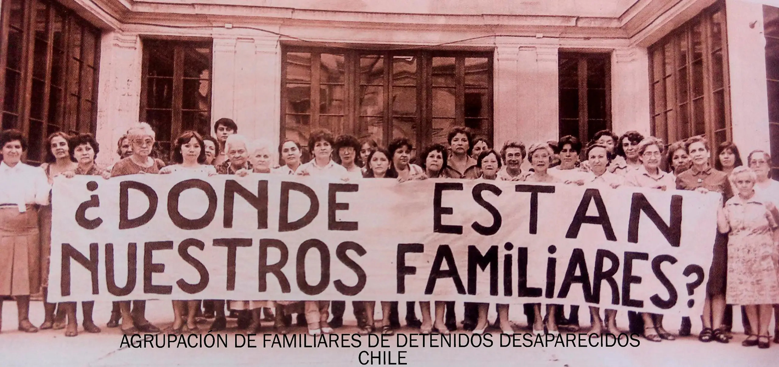 Un grupo de personas sosteniendo una pancarta que dice "¿Dónde están nuestros familiares?", representando a la Agrupación de Familiares de Detenidos Desaparecidos en Chile, en el contexto de búsqueda de desaparecidos durante la dictadura.