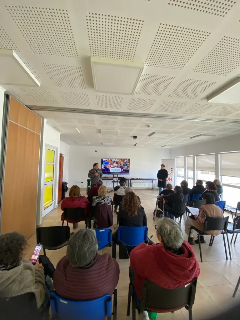 Personas sentadas en una sala de conferencias, mirando a un presentador frente a una pantalla.